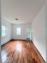 Empty room with a baseboard radiator, healthy amount of natural light, and wood finished floors