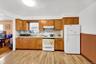 Kitchen with white appliances, light countertops, light wood finished floors, under cabinet range hood, and brown cabinetry