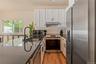 Kitchen featuring dark stone countertops, a sink, white cabinetry, stainless steel appliances, and extractor fan