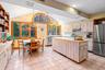 Kitchen with light countertops, open shelves, lofted ceiling, stainless steel appliances, and an island with sink