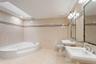 Spacious bathroom featuring a corner jetted tub, dual pedestal sinks, a skylight, and recessed lighting