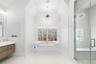 Bathroom with a chandelier, vaulted ceiling, a freestanding tub, vanity, and a stall shower