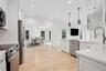 Kitchen featuring a sink, light wood-style floors, an inviting chandelier, stainless steel appliances, and white cabinetry