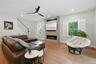 Open-concept living space featuring hardwood flooring, a contemporary ceiling fan, and a linear gas fireplace with stone surround and mounted televisi