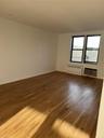 Unfurnished room featuring baseboards, radiator, an AC wall unit, and wood finished floors