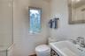 Bathroom featuring tiled shower, a sink, tile walls, and toilet