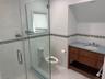 Bathroom featuring toilet, a stall shower, tile patterned floors, tile walls, and vanity