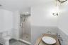 Bathroom featuring a glass-enclosed shower with multiple shower heads, a wall-mounted vanity with a vessel sink, decorative wall tile, and patterned f