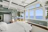 Bedroom featuring a water view, access to outside, wood finished floors, multiple windows, and beam ceiling