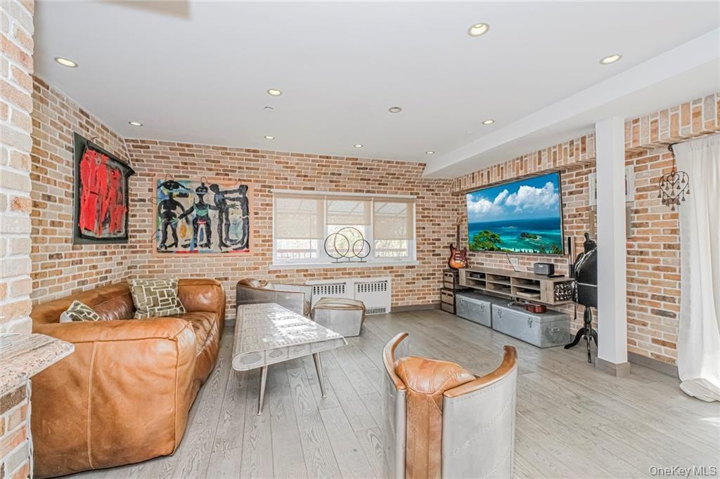 Living room featuring brick wall, recessed lighting, and hardwood / wood-style floors