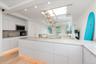 Kitchen featuring modern cabinets, decorative backsplash, light wood-style flooring, white cabinets, and stainless steel microwave
