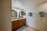Dual mirrors with elegant framing and granite countertops top the double vanity, offering plenty of storage in warm wood cabinetry.