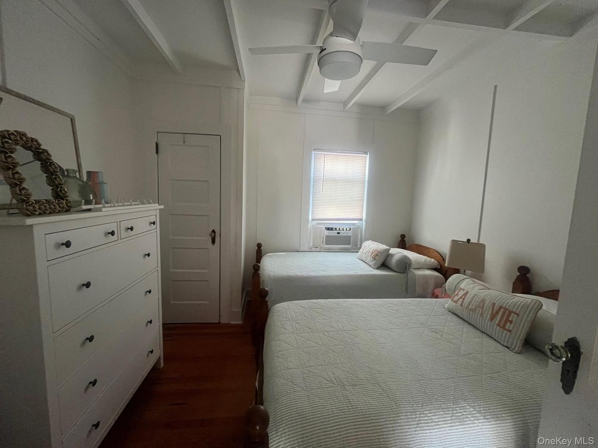 Bedroom featuring beamed ceiling, dark wood-style flooring, and ceiling fan