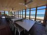 Sunroom with a beach view, ceiling fan, and outdoor dining area