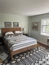 Bedroom with dark wood finished floors and a baseboard heating unit