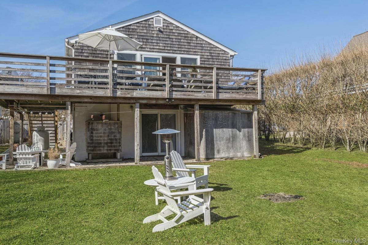 Rear view of house featuring a deck, a lawn, and stairs