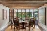 Dining area featuring dark wood-style flooring, beam ceiling, a chandelier, and a wall of windows