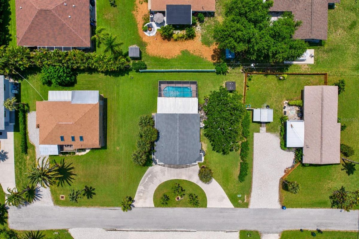 Overhead drone view highlighting the property layout, circular driveway, pool, and spacious yard.