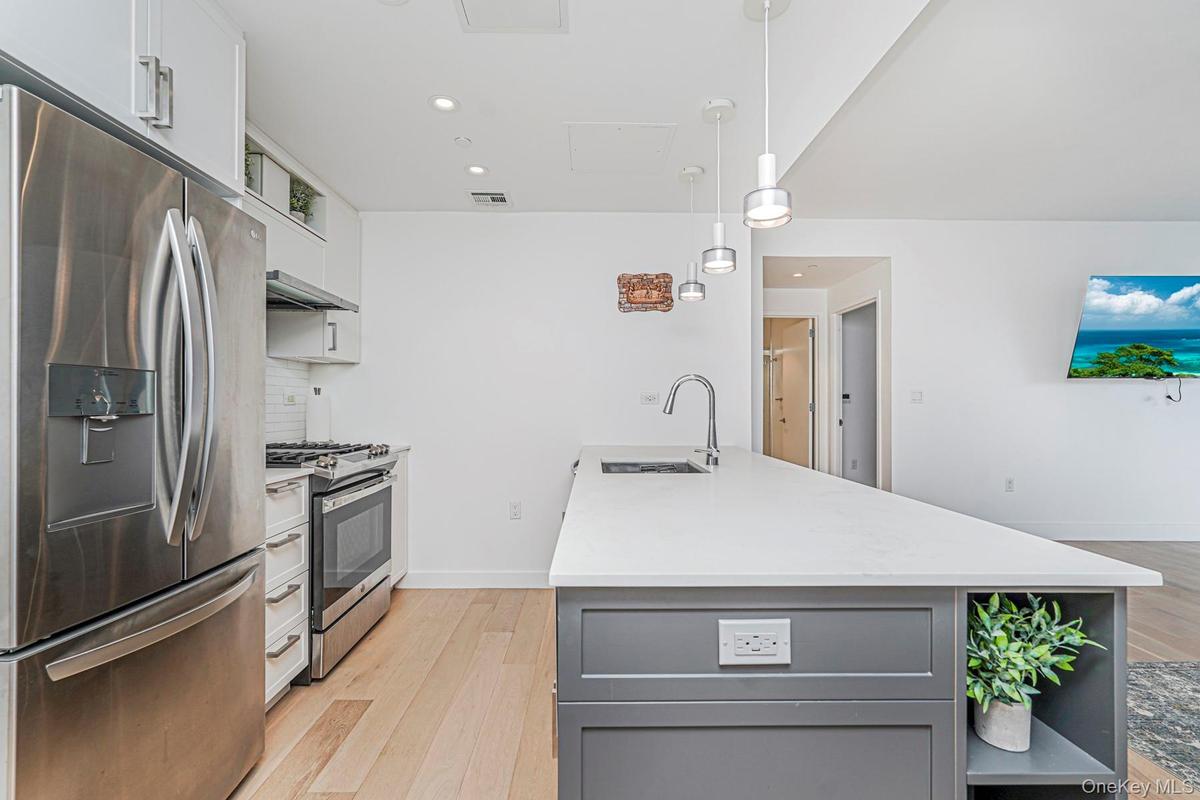 Kitchen featuring gray cabinets, white cabinets, appliances with stainless steel finishes, open shelves, and light wood-type flooring
