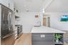 Kitchen featuring gray cabinets, white cabinets, appliances with stainless steel finishes, open shelves, and light wood-type flooring