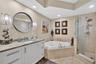Primary bathroom w/ custom wood vanity & upgraded hardware. Beautiful stone vanity counter, wall coverings, sconces, separate medicine cabinet and mir