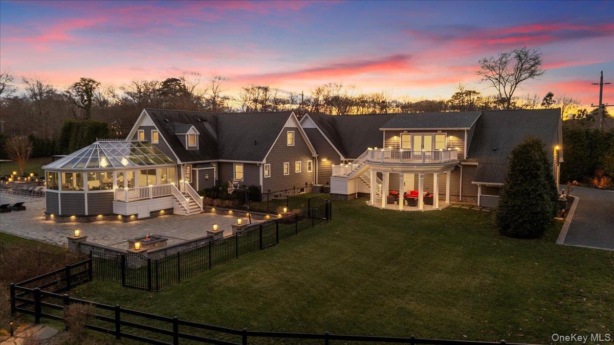 Back of property at dusk with stairs, a patio area, an outdoor fire pit, a fenced backyard, and a sunroom