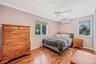 Bedroom with ornamental molding, light wood-style floors, a ceiling fan, a wall mounted AC, and a baseboard radiator