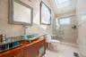 Bathroom featuring tile walls, vanity, a stall shower, a skylight, and light tile patterned floors