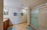 The ensuite bathroom features a large walk-in shower with frosted glass doors, ample space for movement, and dual towel bars for convenience.