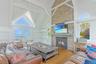 Living area with a fireplace, wood finished floors, high vaulted ceiling, beam ceiling, and plenty of natural light