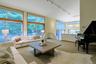 Formal living room with a wall of floor-to-ceiling windows fram picturesque views of the terrace and pond.