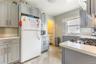 Kitchen featuring gray cabinets, freestanding refrigerator, light tile patterned floors, black microwave, and backsplash