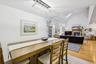 Dining space featuring a glass covered fireplace, high vaulted ceiling, light wood-style floors, and a skylight