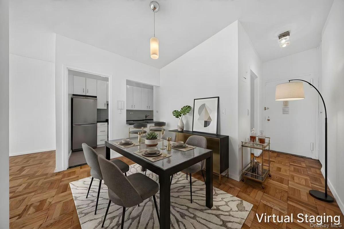 Parquet wood-finish flooring extends throughout this interior space, featuring a recessed kitchen with upper and lower cabinetry