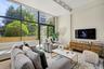 The spacious living room is defined by soaring ceilings and a dramatic wall of glass, filling the space with natural light.