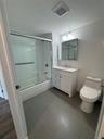 Bathroom featuring bath / shower combo with glass door, vanity, tile walls, and dark tile patterned flooring