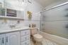 Full bath with tile walls, vanity, bath / shower combo with glass door, toilet, and tile patterned floors
