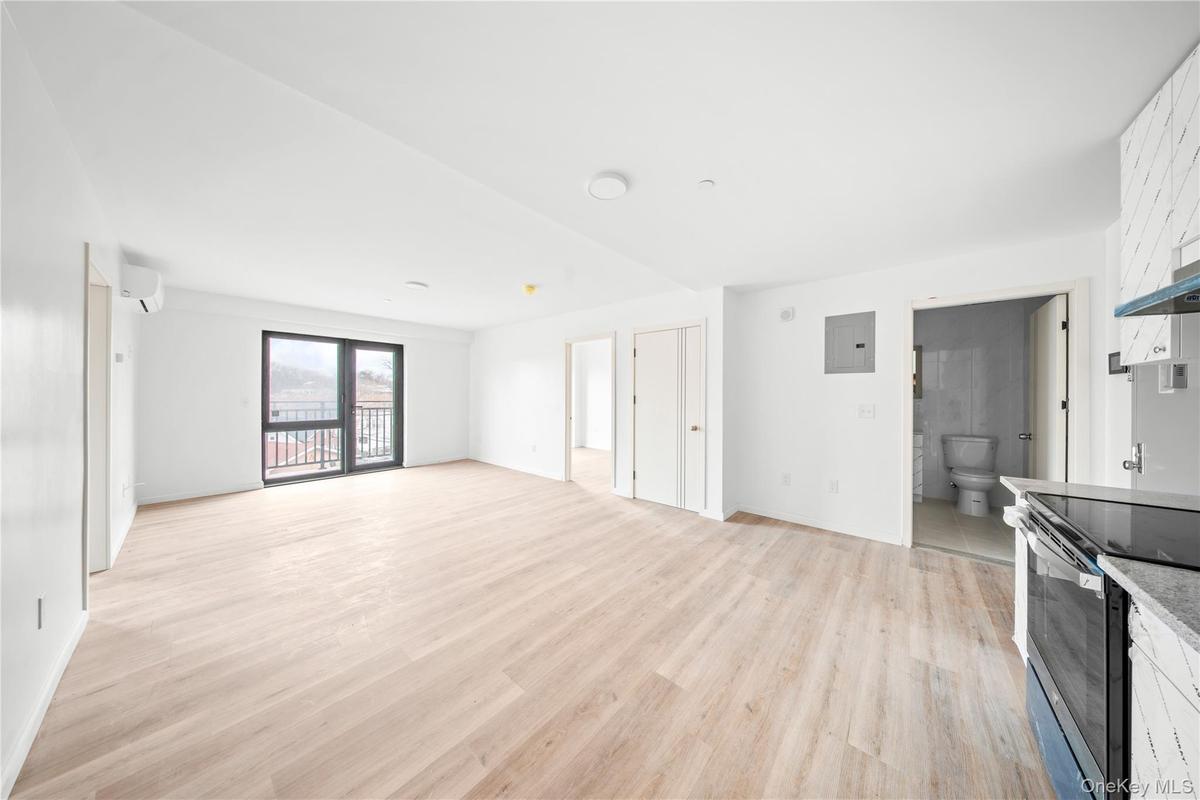 Unfurnished living room with light wood finished floors, electric panel, and a wall mounted air conditioner