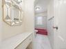Bathroom featuring white tile flooring, tiled walls with an accent border, a window, and a built-in bathtub