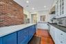 Kitchen with dark hardwood / wood-style flooring, backsplash, brick wall, blue cabinets, and built in appliances