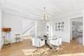 Dining space with a chandelier, light wood-style floors, a decorative wall, wainscoting, and beam ceiling