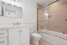 Bathroom featuring wainscoting, toilet, vanity, and shower / bath combination with glass door
