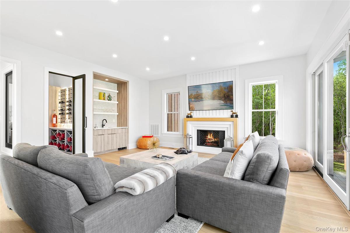 Living room featuring recessed lighting, light wood-style floors, a warm lit fireplace, and bar area