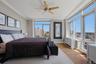 Spacious primary bedroom featuring extensive window-lines, light wood-finish flooring, and a ceiling fan