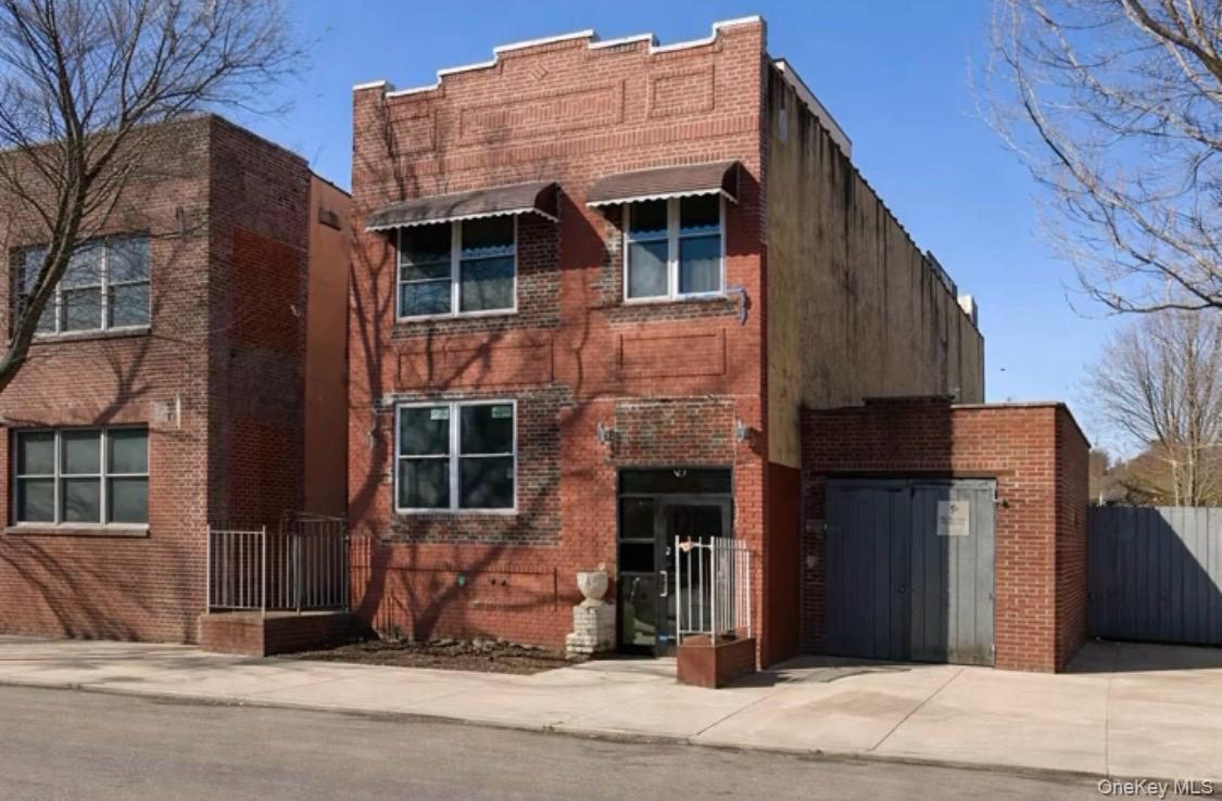 Brick facade building with multiple windows, awnings, and an integrated garage structure