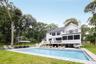 Rear view of house with a balcony, a patio, an outdoor pool, and a chimney