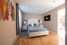 Bedroom with baseboard heating, a drop ceiling, and light hardwood / wood-style flooring