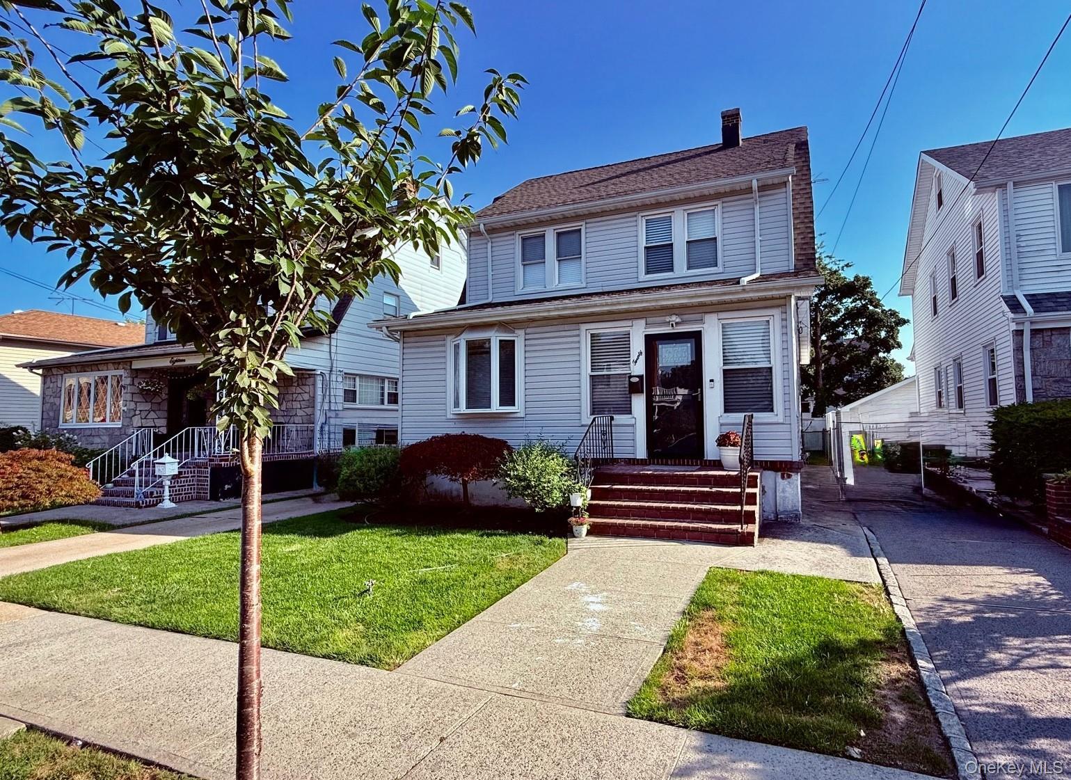 Two-story residence with light-colored siding, dark shingle roof, and a paved driveway