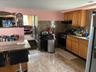Kitchen featuring range, brown cabinets, range hood, and black refrigerator