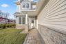 Property entrance featuring a shingled roof, a lawn, and stone siding
